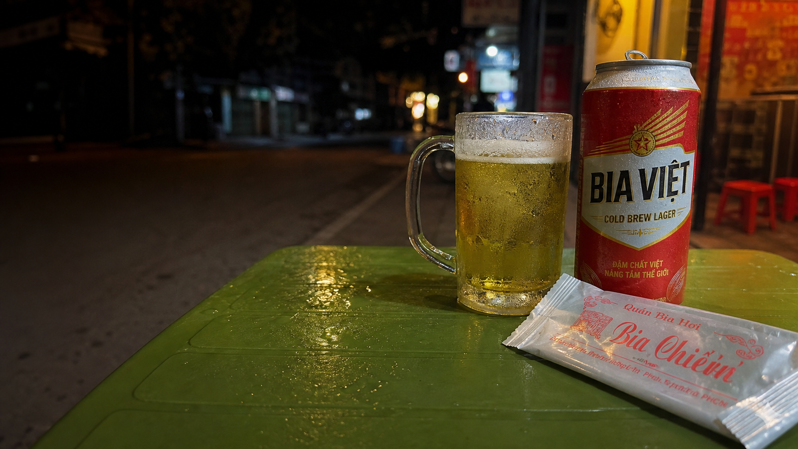 ベトナムの路上ビアホイで、BIA VIỆTの缶とビールジョッキ、Bà Chiếnのおしぼりが並ぶテーブル
